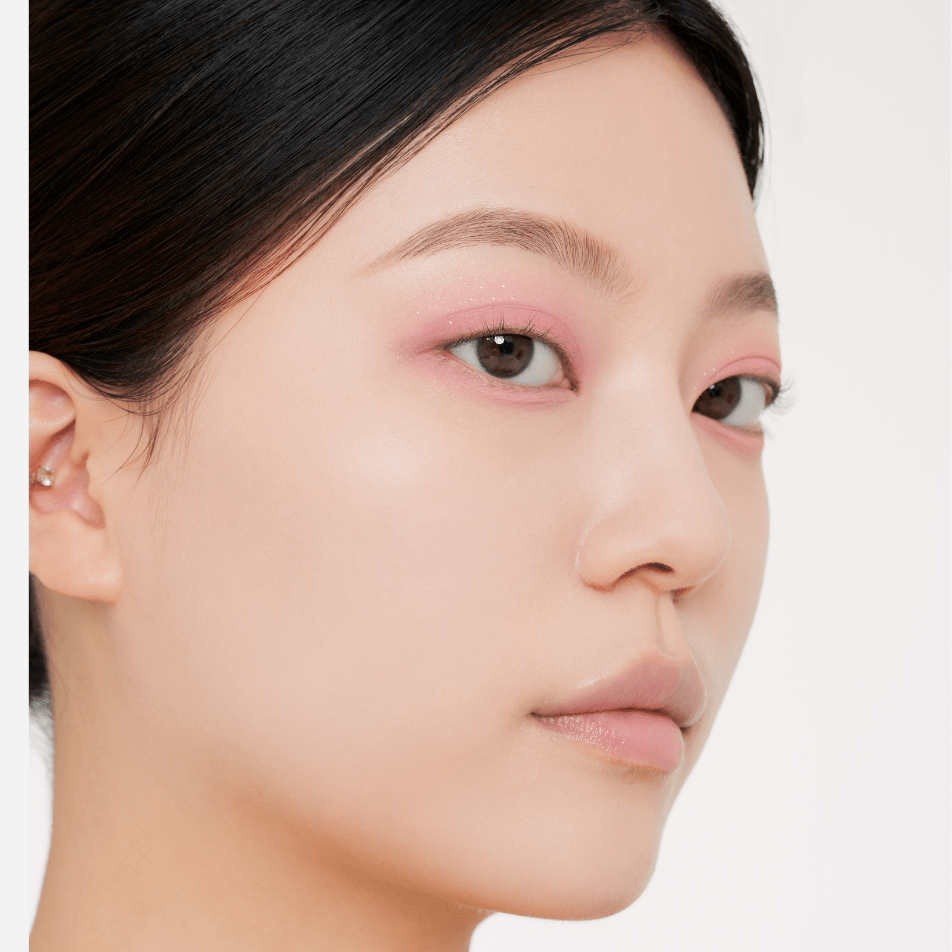 Modella con trucco rosa che tiene la MUZIGAE MANSION Twist Pot Eye Palette nella mano con guanto nero